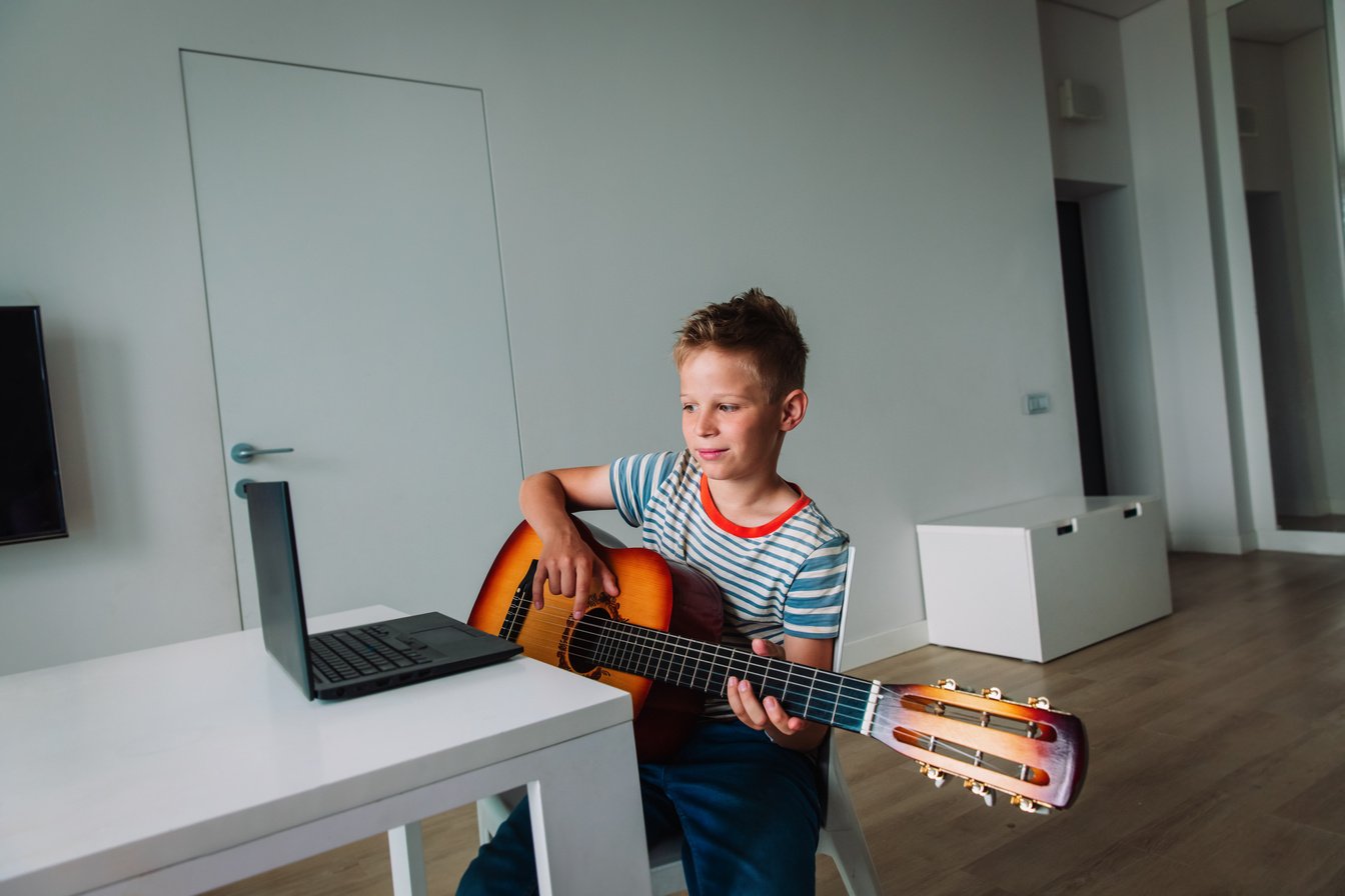 kid having guitar lesson online, remote music class